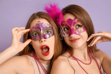 Leylak arkaplanda karnaval maskeli güzel genç kadınlar