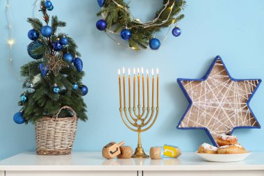 Oturma odasında köknar ağacı ve geleneksel Hanuka süslemeleri olan beyaz masa.