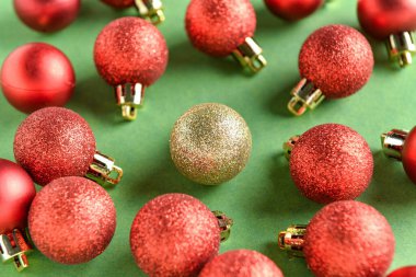 Kırmızılar arasında yeşil arka planda bir altın Noel topu. Eşsizlik kavramı