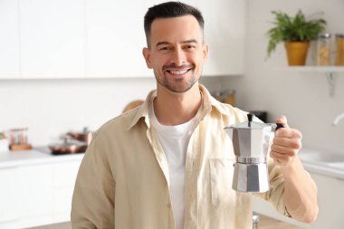 Modern mutfakta gayzer kahve makinesi olan yakışıklı bir adam.