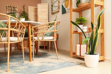 Bitkileri, yemek masası ve raf ünitesi olan rahat bir odanın içinde.