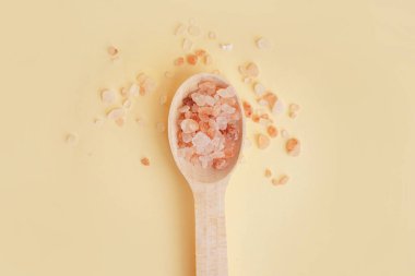 Tahta kaşık, Himalaya pembe tuzu ve sarı arka plan.