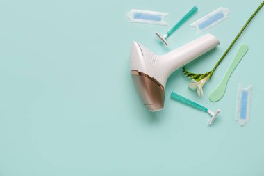 Usturalı modern fotoepilatör, balmumu şeritler ve turkuaz arka planda çiçek.