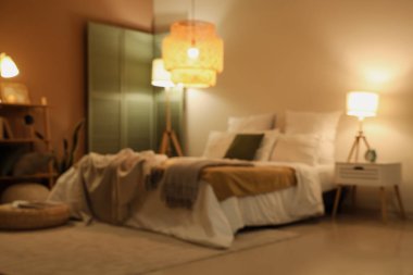 Yatak odasının bulanık görüntüsü, yatakta ekose kumaşlar ve gece lambaları.