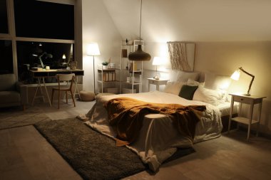 Yatak odasının içinde iş yeri ve geceleri parlayan lambalar.