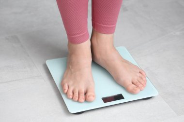 Evde terazinin üzerinde duran genç bir kadın. Kilo verme konsepti