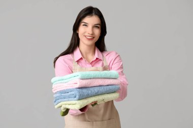 Gri arka planda temiz havluları olan güzel genç bir kadın.