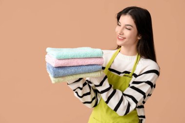 Kahverengi arka planda temiz havluları olan güzel genç bir kadın.