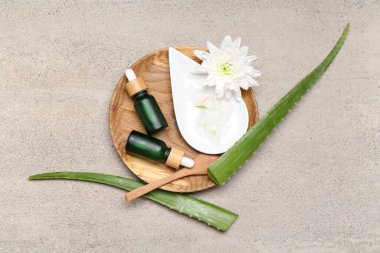 Temel yağ şişeleri ve grunge arka planda aloe vera yaprakları bileşimi