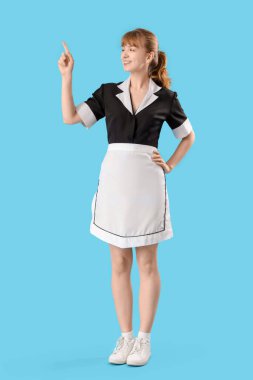 Genç oda hizmetçisi mavi arka planda bir şeye bakıyor.