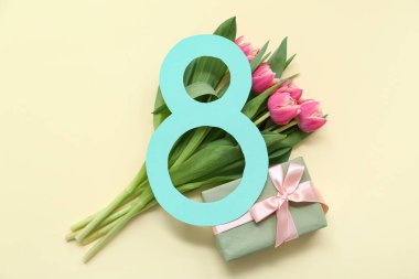 Hediye kutusu ve sarı arka planda güzel laleler olan kağıttan yapılmış 8 figür. Uluslararası Kadınlar Günü