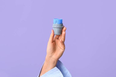 Leylak arka planında glikoz sensörü aplikatörü olan bir kadın eli. Diyabet kavramı