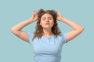 Güzel genç bir kadın mavi arka planda saç derisi masaj aleti kullanıyor.