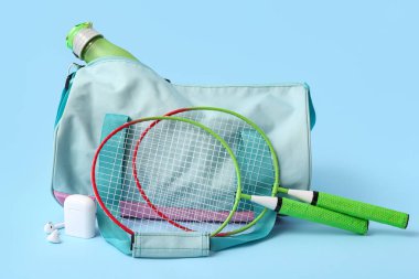 Spor kıyafetleri ve mavi arka planda tenis raketleri olan spor çantası.