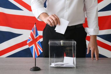 Oy sandığının yanında İngiliz bayrağı taşıyan genç adam oy kullanma merkezindeki masada, yakın çekim