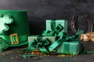 Leprikon şapkalı hediye kutuları, pullar ve siyah grunge arka planda altın. Aziz Patrick Günü