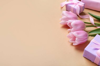 Bej arka planda hediye kutuları ve pembe laleler