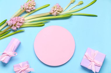 Hediye kutuları, sümbül çiçeği ve mavi arka planda boş tebrik kartı. Yakın çekim.