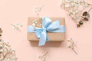 Güzel paketlenmiş hediye kutusu ve bej arka planda çiçekler
