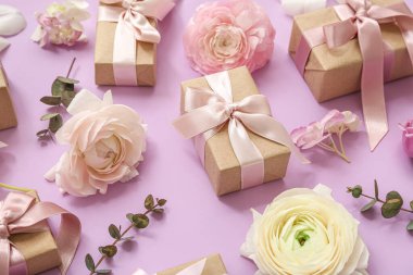 Paketlenmiş hediye kutuları ve pembe arka planda çiçekleri olan zarif kompozisyon