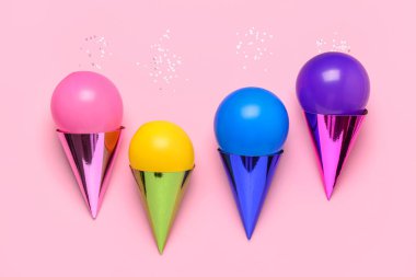 Pembe arka planda balonları olan parti şapkaları.