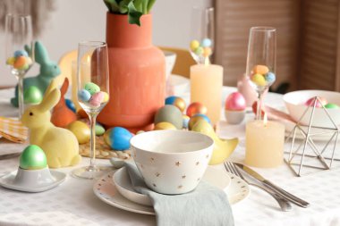 Mumlar, boyanmış yumurtalar ve Paskalya tavşanlarıyla süslü şık bir masa.