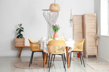 Yemek odasında çiçek vazosu, boyanmış yumurta ve Paskalya tavşanları olan şenlik masası.