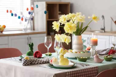 Çiçek vazosu, peçete ve paskalya tavşanları şık bir mutfak ortamında.