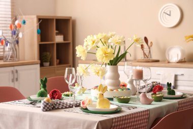 Çiçek vazosu, paskalya tavşanı, mum ve mutfakta boyanmış yumurtalarla süslü masa dekorları.