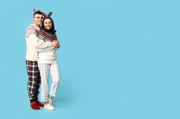 Feliz Jovem Casal Pijama Natal Abraçando Fundo Azul — Fotografia de Stock