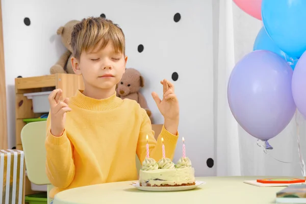 Cute little boy with Birthday cake making wish at home