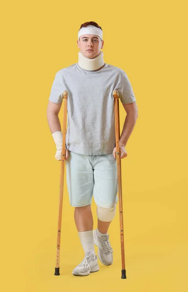 Verletzter Junger Mann Nach Unfall Mit Krücken Auf Gelbem Grund — Stockfoto