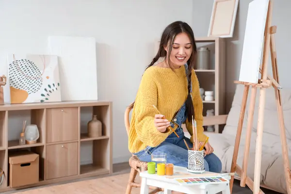 Female Asian artist painting with canvas at home
