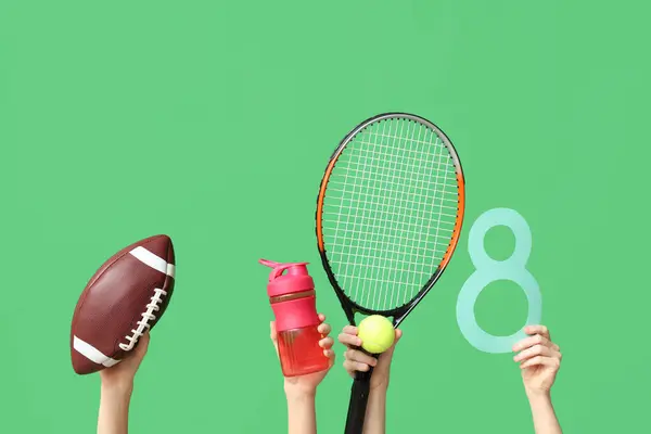 Female hands with paper figure 8 and sports equipment for International Women's Day on green background