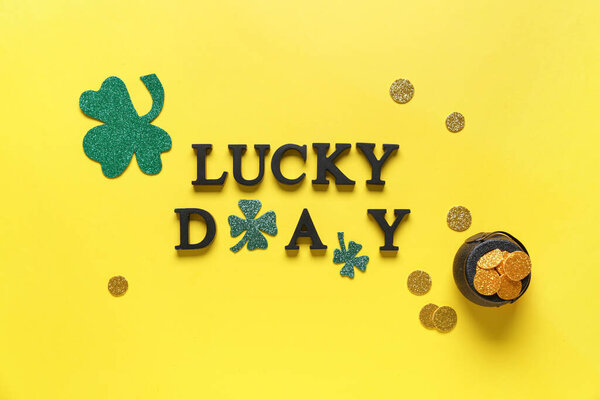 LUCKY DAY Words With clovers and pot of golden coins for St. Patrick 's celebration on yellow background