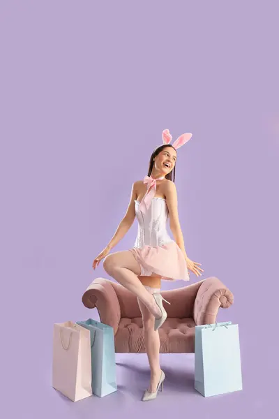 Sexy Young Woman Bunny Costume Shopping Bags Armchair Lilac Background — Stock Photo, Image
