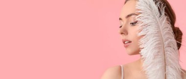 Güzel, genç bir kadın pembe arka planda yumuşak bir tüy tutuyor ve mesaj için yeri var. Epilasyon kavramı