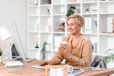 Ofiste çalışan olgun bir kadın programcı ve bir fincan kahve.