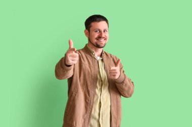 Yeşil arka plandaki izleyiciye bakan yakışıklı adam