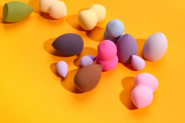 Turuncu arka planda farklı makyaj süngerleri