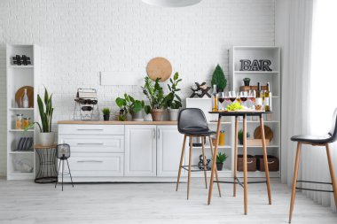 Mutfağın içinde tezgah, masa ve şarap var.