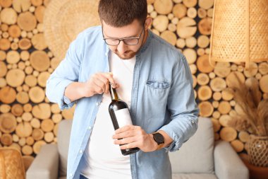 Sommelier oturma odasında tirbuşonla şarap şişesi açıyor.