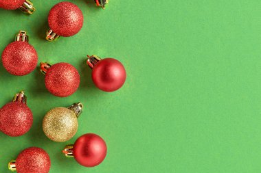 Kırmızılar arasında yeşil arka planda bir altın Noel topu. Eşsizlik kavramı