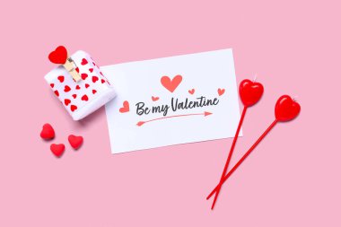 Kutlama kartı, hediye kutusu ve pembe arka planda Sevgililer Günü kutlaması için mumlar olan kompozisyon