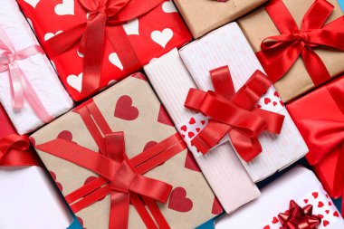 Kalpli farklı hediye kutuları ve arka planda kırmızı kurdeleler, yakın plan. Sevgililer Günü kutlaması