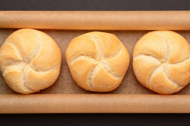 Siyah zemin üzerinde lezzetli kayzer ruloları olan kağıt fırını.