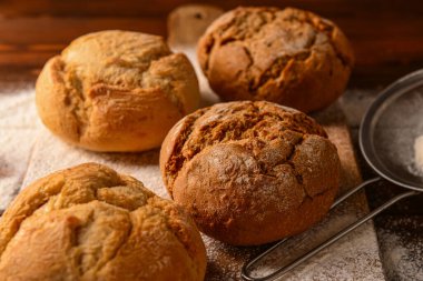 Tahta arka planda taze lezzetli çörekler ve un, yakın plan.