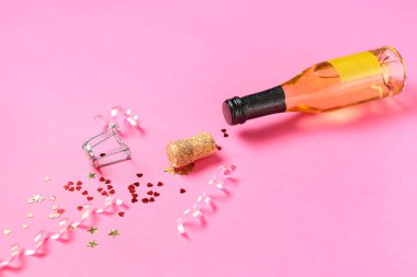 Bir şişe mantarlı şampanya ve pembe arka planda konfeti. Sevgililer Günü kutlaması