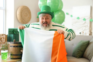 Aziz Patrick Günü 'nde evinde İrlanda bayrağı taşıyan şapkalı olgun bir adam.