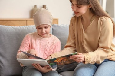 Annesi evde kitap okurken kemoterapiden sonra küçük bir kız. Uluslararası Çocukluk Kanser Günü